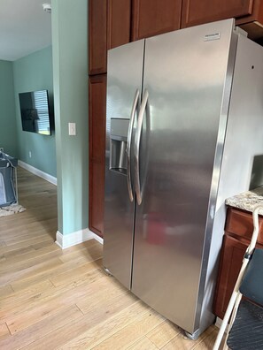 A stainless steel refrigerator in a kitchen with wooden cabinets and a tiled backsplash. - Private Berkshire Retreat 9 Acres, Fenced Yard & Dogs Welcome (Otis)