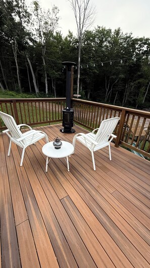 A wooden deck with two white chairs and a table, surrounded by a wooden railing and trees. - Private Berkshire Retreat 9 Acres, Fenced Yard & Dogs Welcome (Otis)