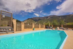 A swimming pool with a mountain backdrop, surrounded by a fenced area with lounge chairs. - Welcome to your beautifully renovated Copper Mountain getaway! (Copper Mountain)