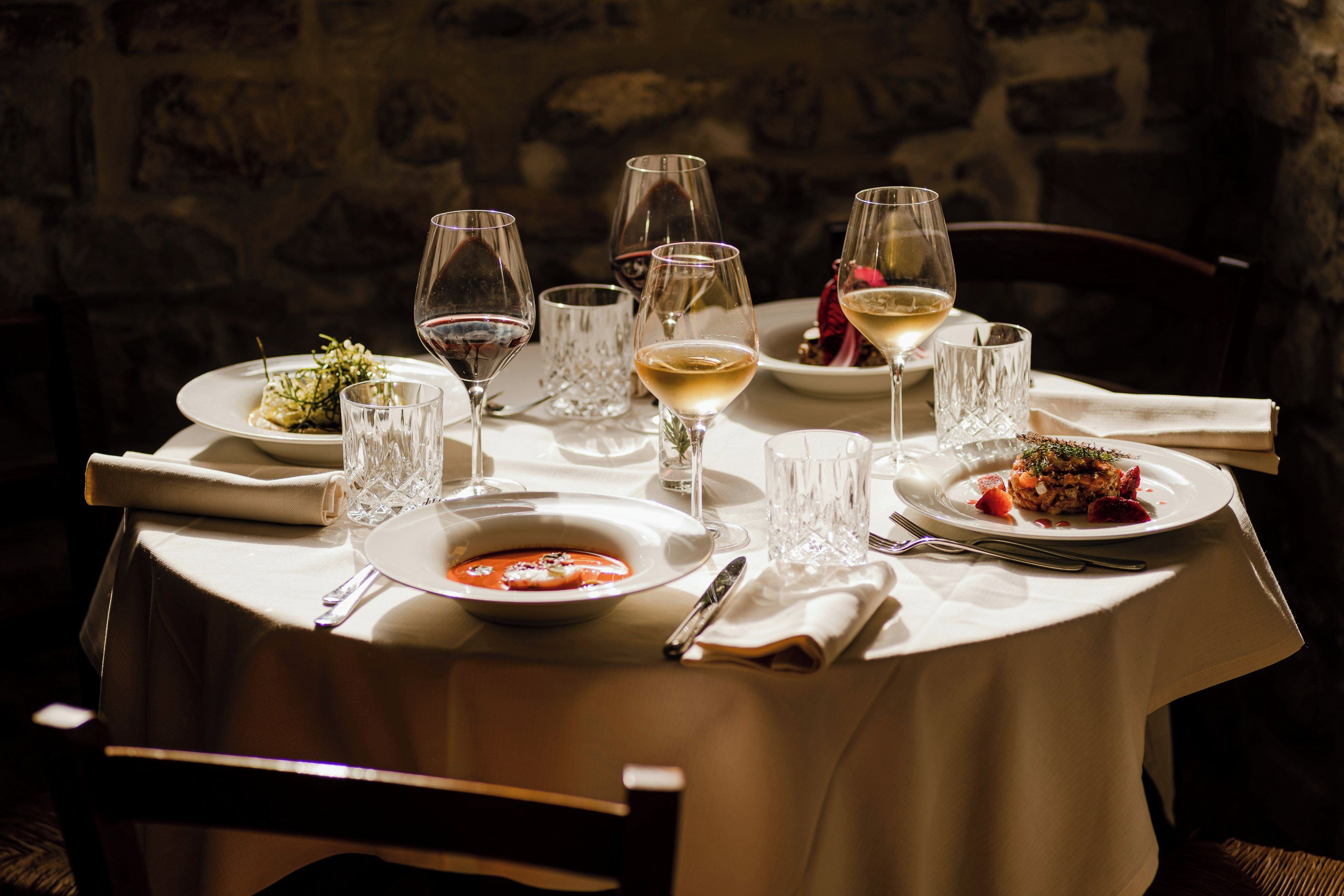 Una tavola imbandita per un pasto, con diversi bicchieri di vino, piatti di cibo e posate.