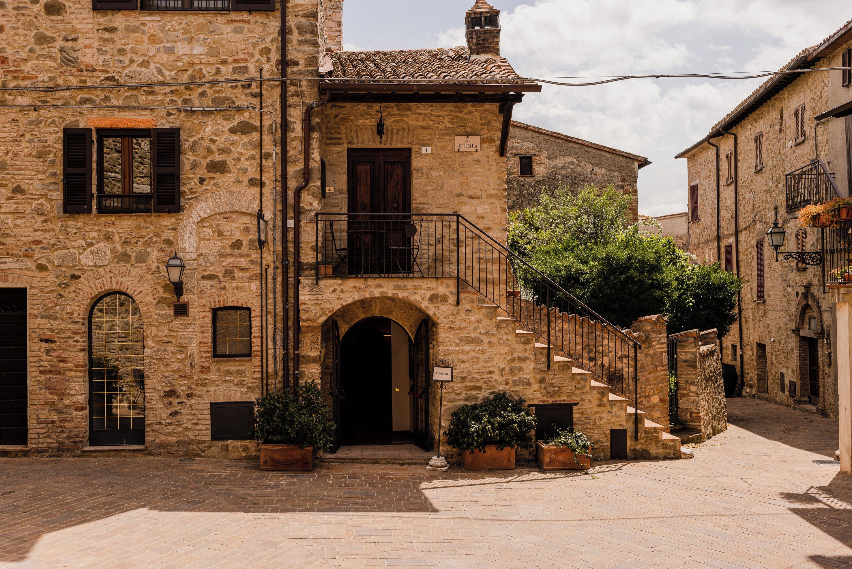 Un edificio in pietra con un ingresso centrale, una scala che conduce a un piano superiore e un piccolo balcone con ringhiera.