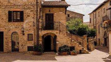 Un edificio in pietra con un ingresso centrale, una scala che conduce a un piano superiore e un piccolo balcone con ringhiera.