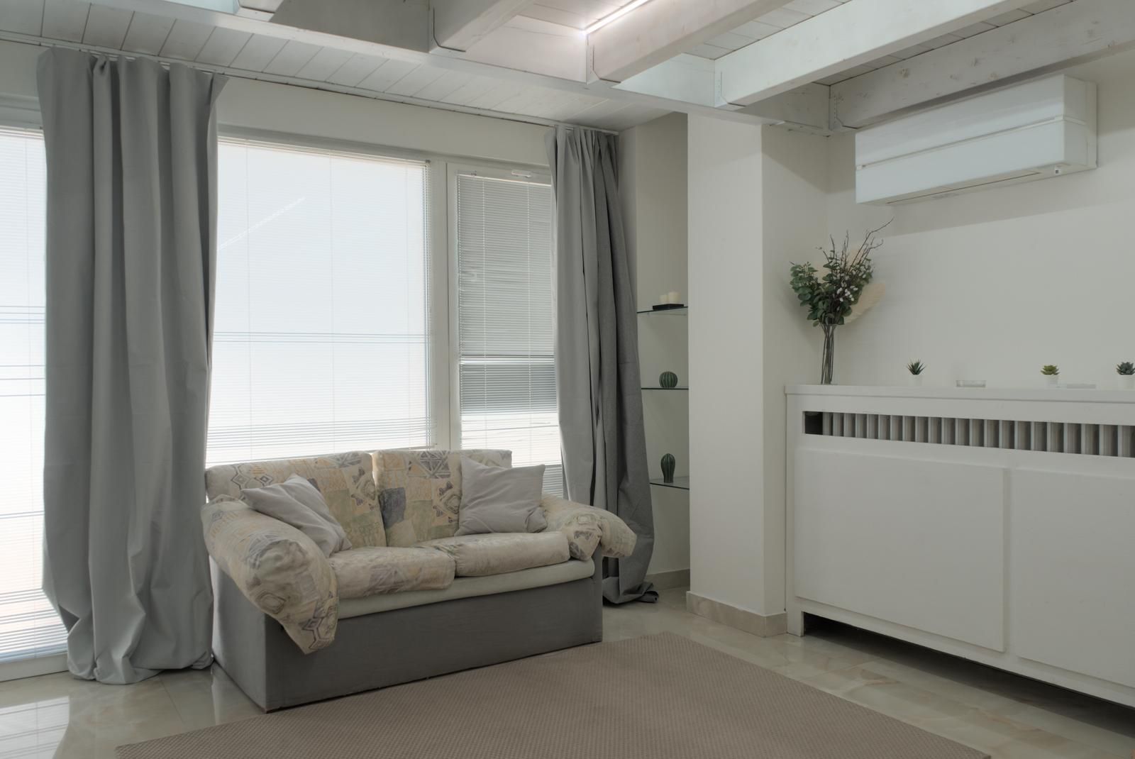 A modern living room with a sofa, a radiator, and a window with curtains.