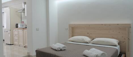 A modern bedroom with a wooden headboard, a bed with two pillows, and a neatly made bedspread.