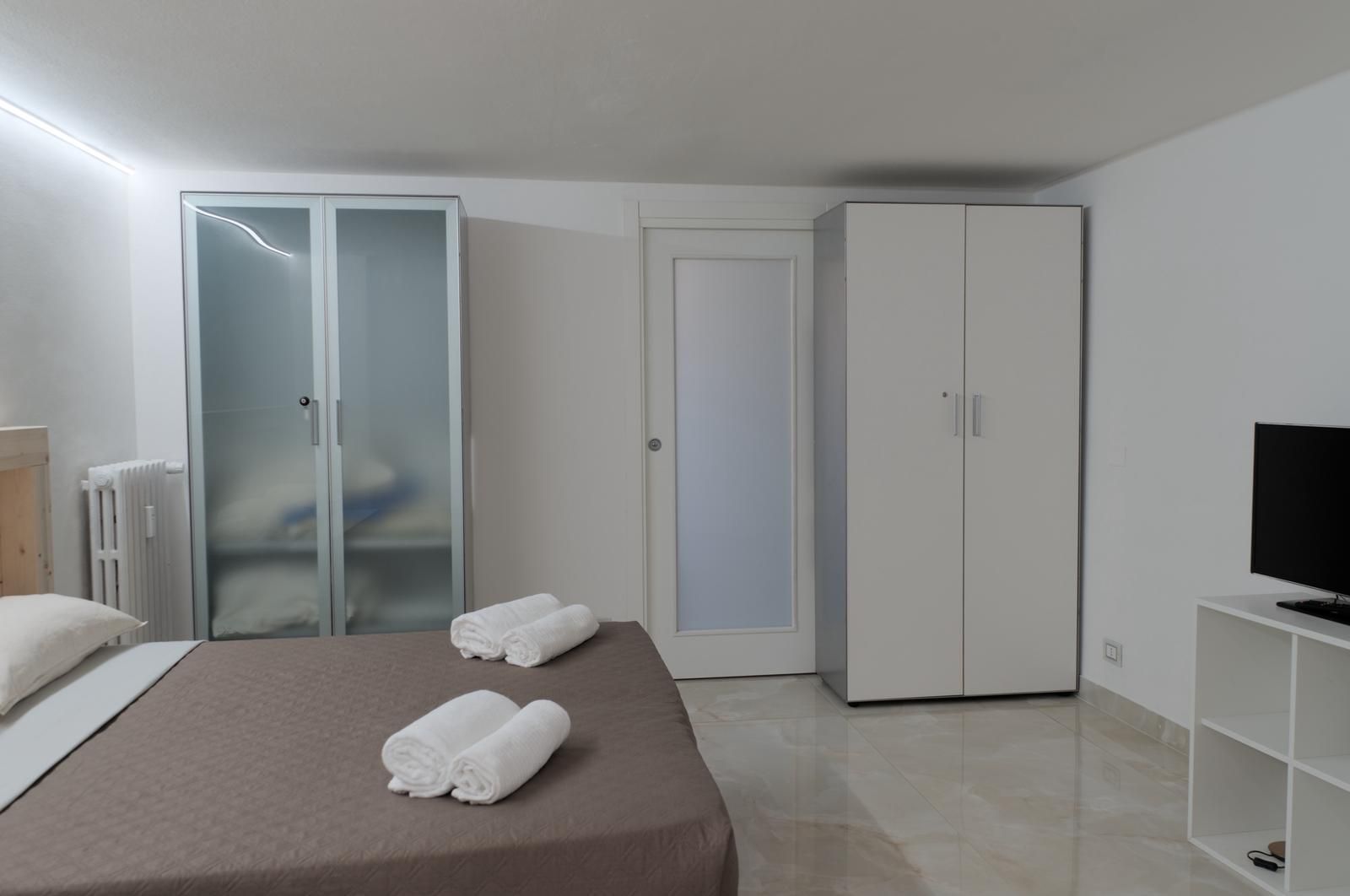 Une chambre d’hôtel moderne équipée d’un lit, de deux armoires, d’une télévision et d’un radiateur.