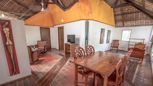 A spacious room with a wooden dining table, chairs, a television, and artwork on the walls. - Bamboo Bungalows (Boracay Island)