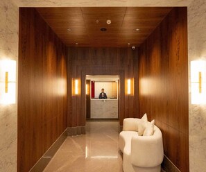A hotel reception area with a wooden interior, a reception desk, and two white armchairs. - Executive Room Checkin Amritsar (Amritsar)