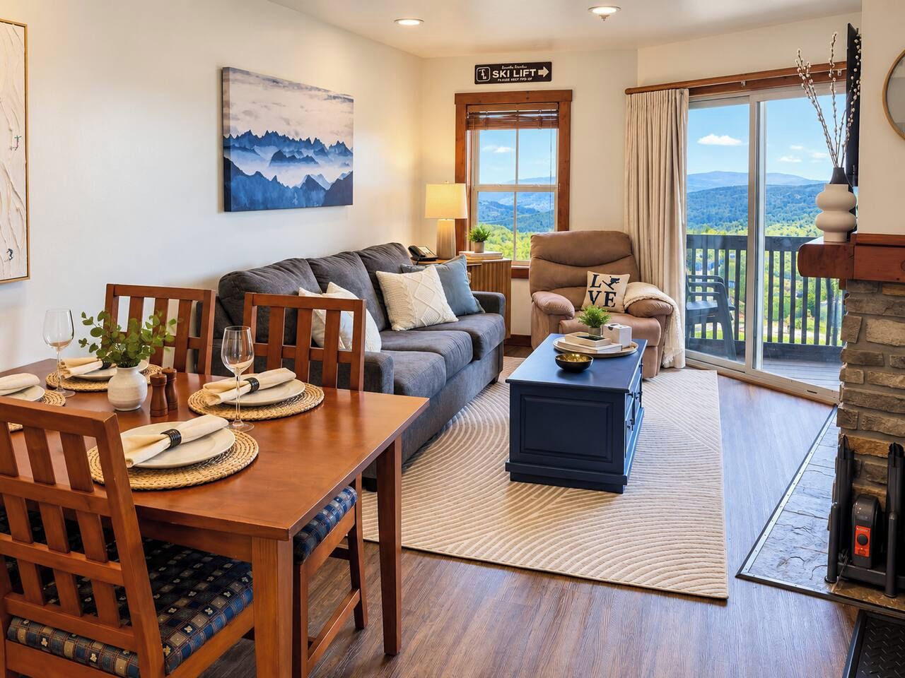 A cozy living room with a dining area, a fireplace, and a scenic view through the windows.