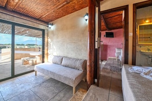 A room with a sofa, a bench, a wooden ceiling, a wall-mounted TV, and a bathroom with a mirror and sink. - Kissamos Windmills (Kissamos)