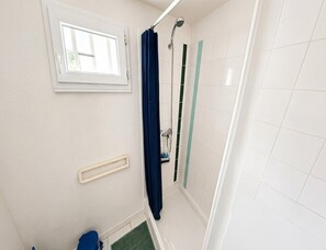 Ein Badezimmer mit Dusche, Fenster und Handtuchhalter.
