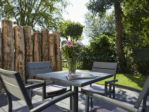 Eine Terrasse im Freien mit Tisch, Stühlen und einem Blumenstrauß.