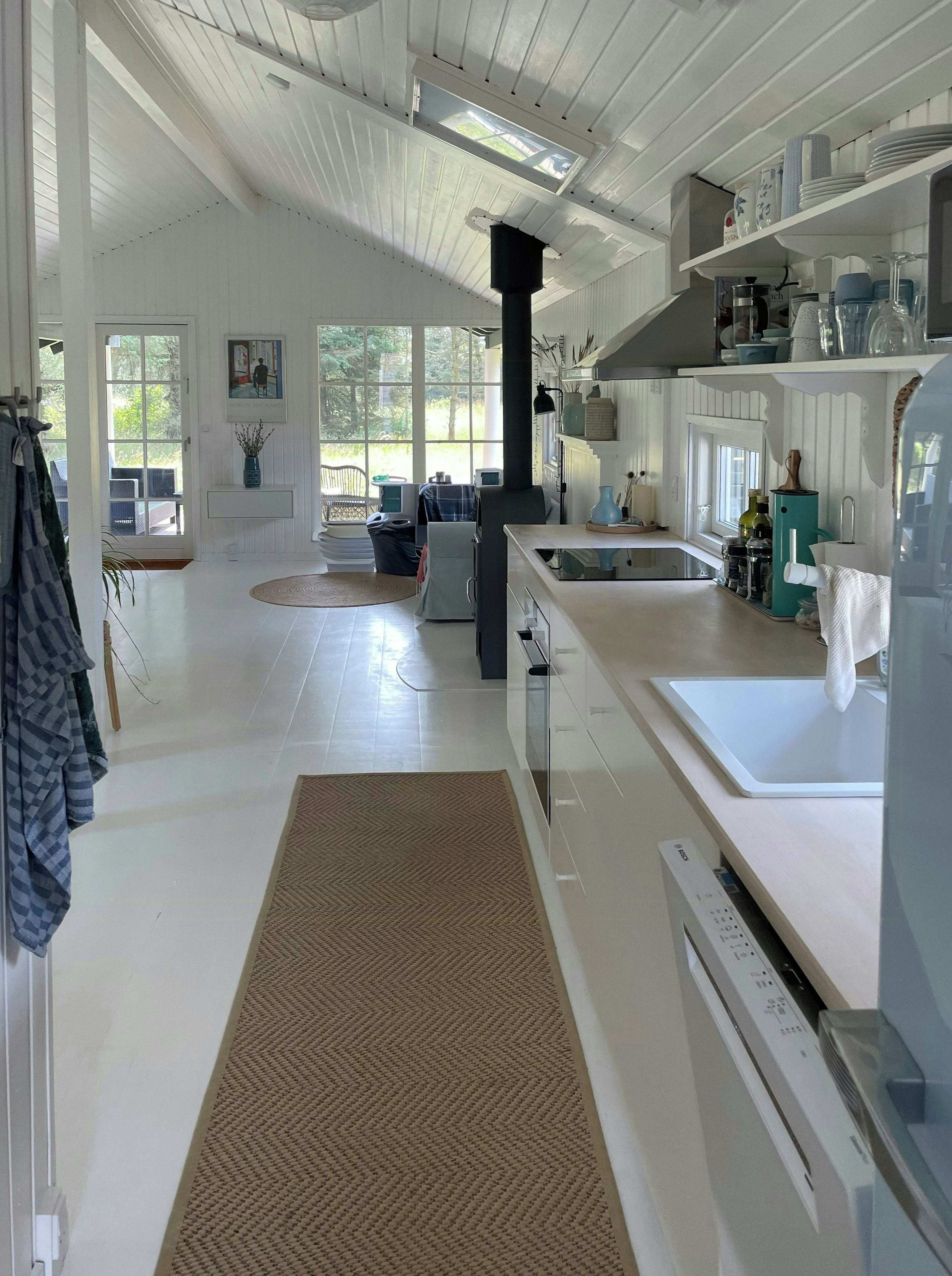 A spacious kitchen with a central island, a built-in oven, and a window overlooking a garden.