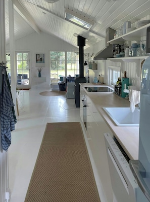 A spacious kitchen with a central island, a built-in oven, and a window overlooking a garden. - Holiday home at Rubjerg Knude Fyr (Løkken)