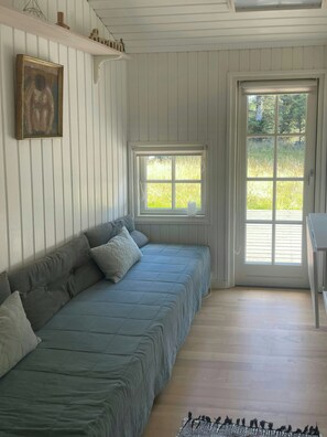 A room with a bed, a window, a door, and a small table. - Holiday home at Rubjerg Knude Fyr (Løkken)