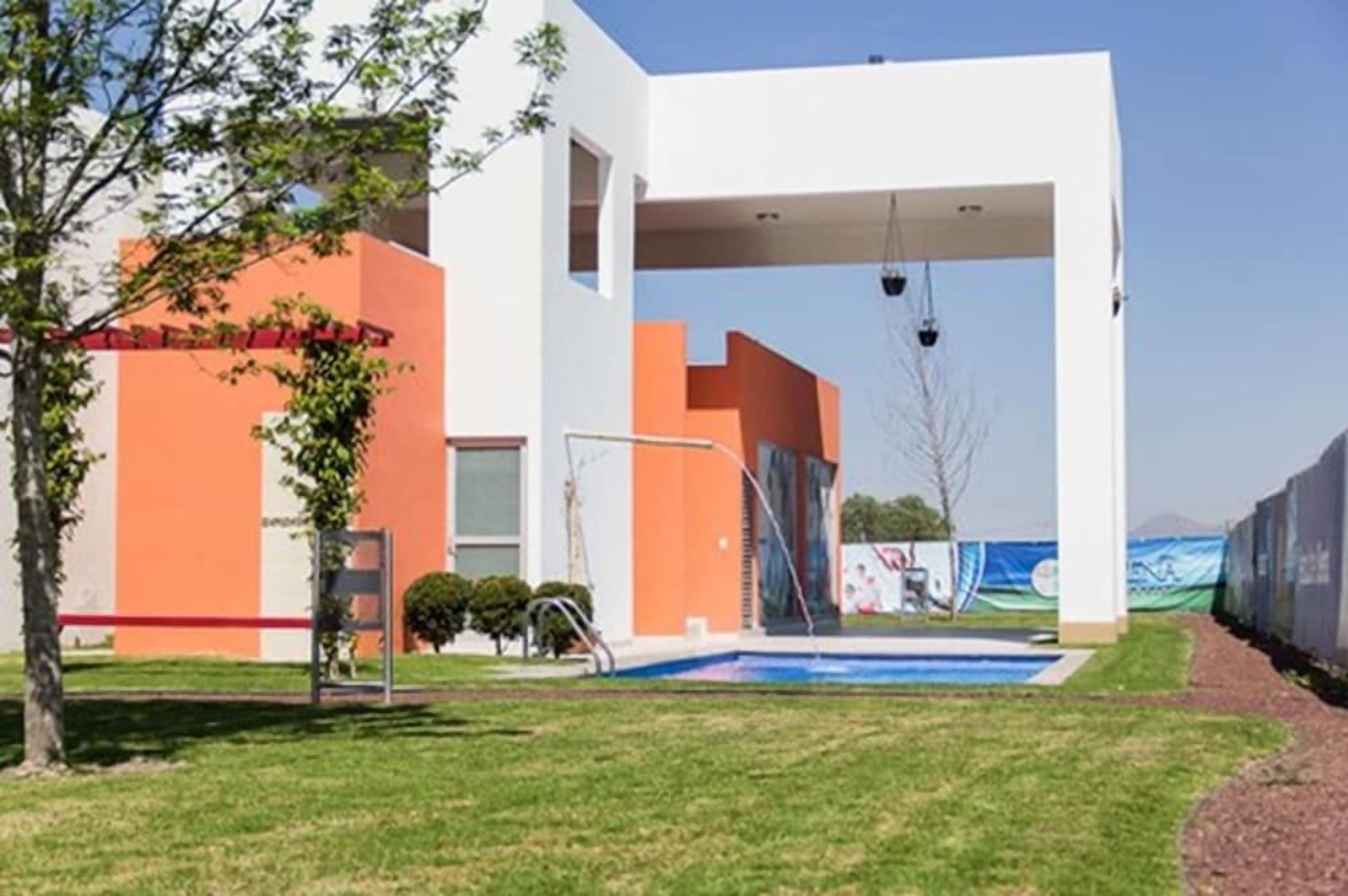 Un edificio moderno con piscina, zona cubierta y una barrera roja.
