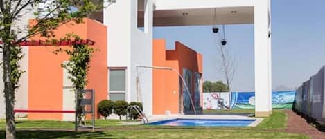 A modern building with a swimming pool, a covered area, and a red barrier.