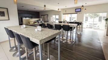 Una cocina moderna con encimeras de granito, electrodomésticos de acero inoxidable y taburetes de bar.