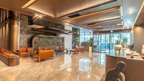 Een moderne lobby met een receptiebalie, zithoek en een groot raam met uitzicht.