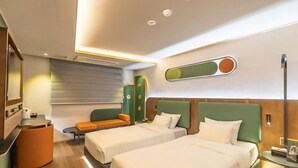 Een hotelkamer met twee bedden, een zithoek, een tafeltje en een wandlamp.