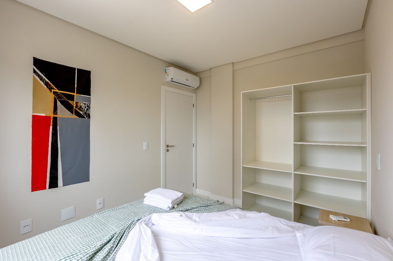 Een hotelkamer met een bed, een kledingkast, een wandairconditioner en een schilderij.