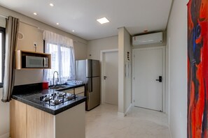 Una cocina compacta equipada con estufa a gas, microondas, refrigerador y pileta.