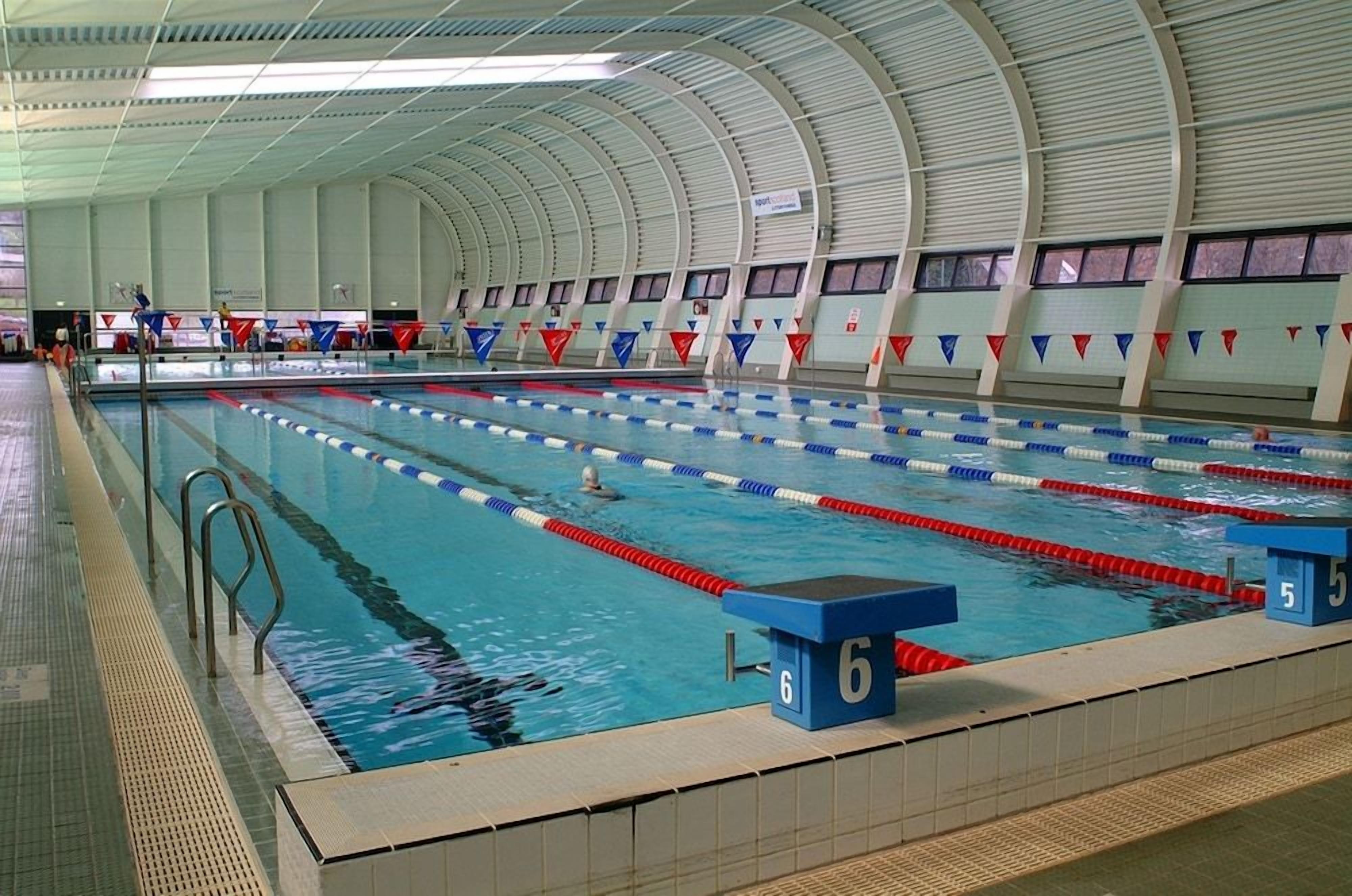 An indoor swimming pool with lane dividers and numbered starting blocks.