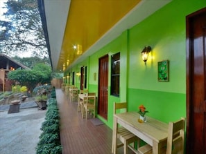 A corridor with a green wall, wooden furniture, and a small table with a flower. - Butterfly Totem Guesthouse (Puerto Princesa)