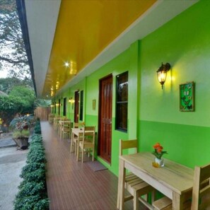 Un pasillo con mesas y sillas de madera, paredes verdes y suelo de madera.