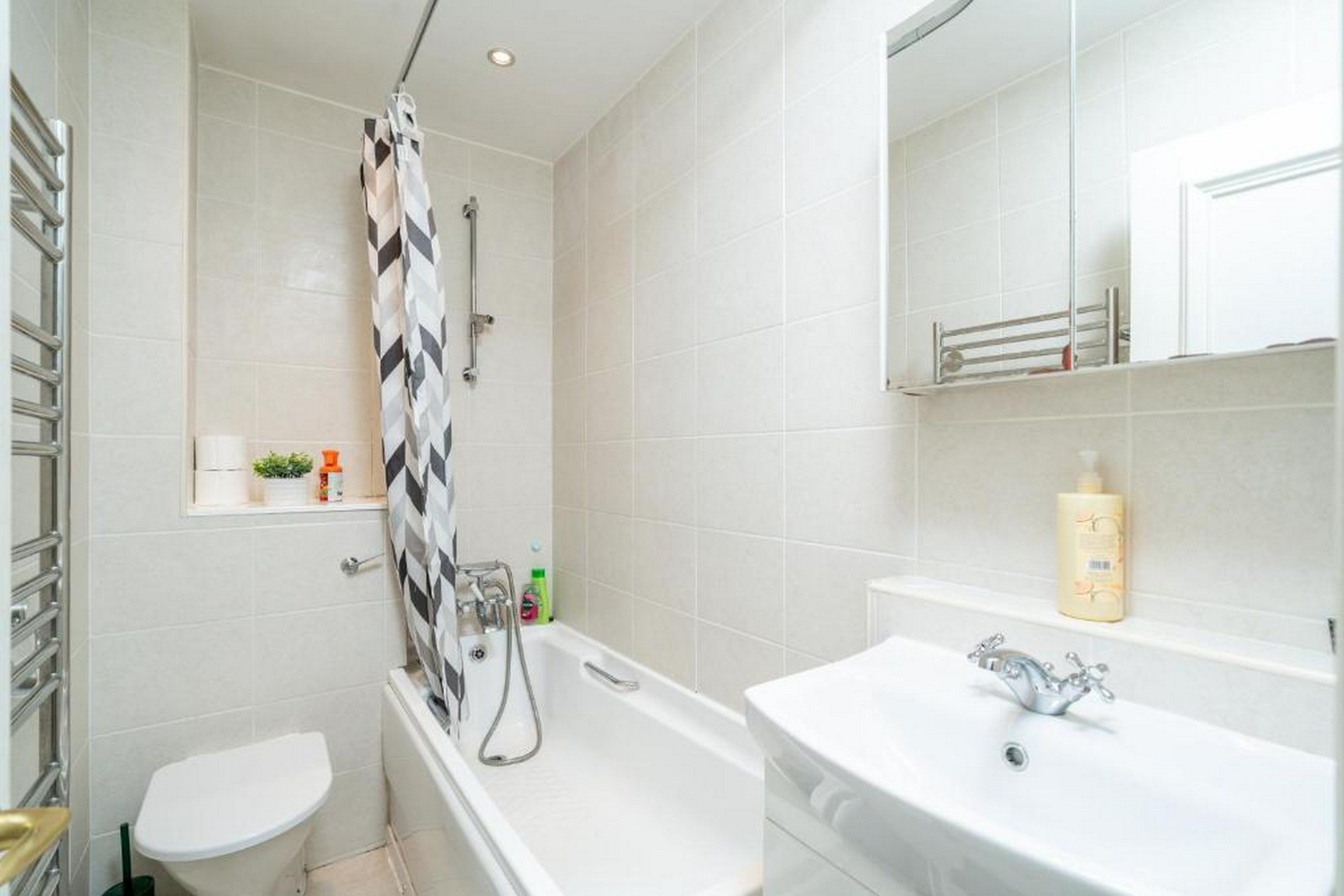 Un baño con ducha, inodoro y lavamanos, todo en color blanco.