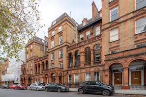 A row of red brick buildings with arched windows and a central entrance. - Top-Floor 1-Bed Apt. in South Kensington (London)