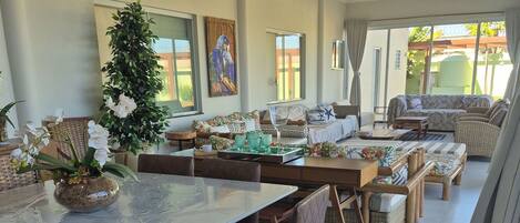 A spacious dining area with a long table, multiple chairs, and a decorative plant centerpiece.