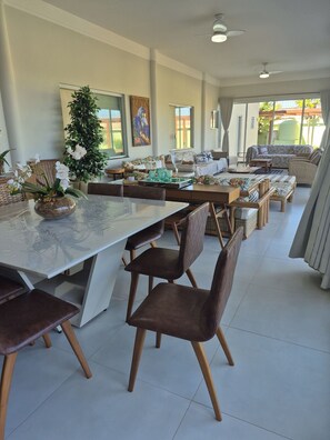 A spacious dining area with a long table, multiple chairs, and a decorative plant centerpiece.
