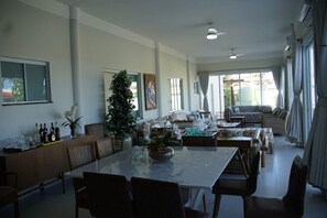 Un salón espacioso con una mesa de comedor, sillas, sofás y un gran ventanal.