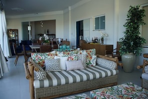 A living room with a sofa, chairs, a dining table, and a large potted plant.
