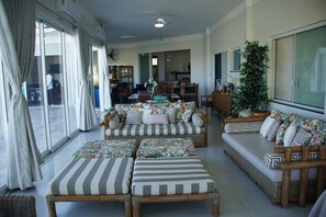 Amplia sala de estar con un conjunto de sofás, una mesa de comedor y un gran ventanal con cortinas.