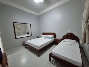A bedroom with two beds, a nightstand, a dresser, a mirror, and a ceiling light.