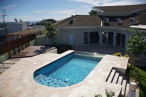 A swimming pool with a curved edge, surrounded by a patio area with a tiled floor.