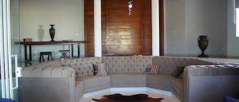 Una sala de estar moderna con un sofá modular, una puerta de cristal y piso de madera.