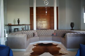 Un salon moderne avec un canapé d’angle, une porte en verre et un plancher en bois.