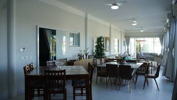Une salle à manger spacieuse avec un grand ventilateur de plafond, une grande fenêtre avec des rideaux et une vue sur l’extérieur.