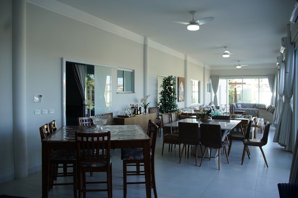 A spacious dining area with a high ceiling fan, a large window with curtains, and a view of the outdoors.