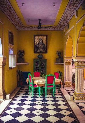 A dining area with a checkered floor, a table with chairs, and a ceiling fan. - Hotel Diggi Palace (Jaipur)