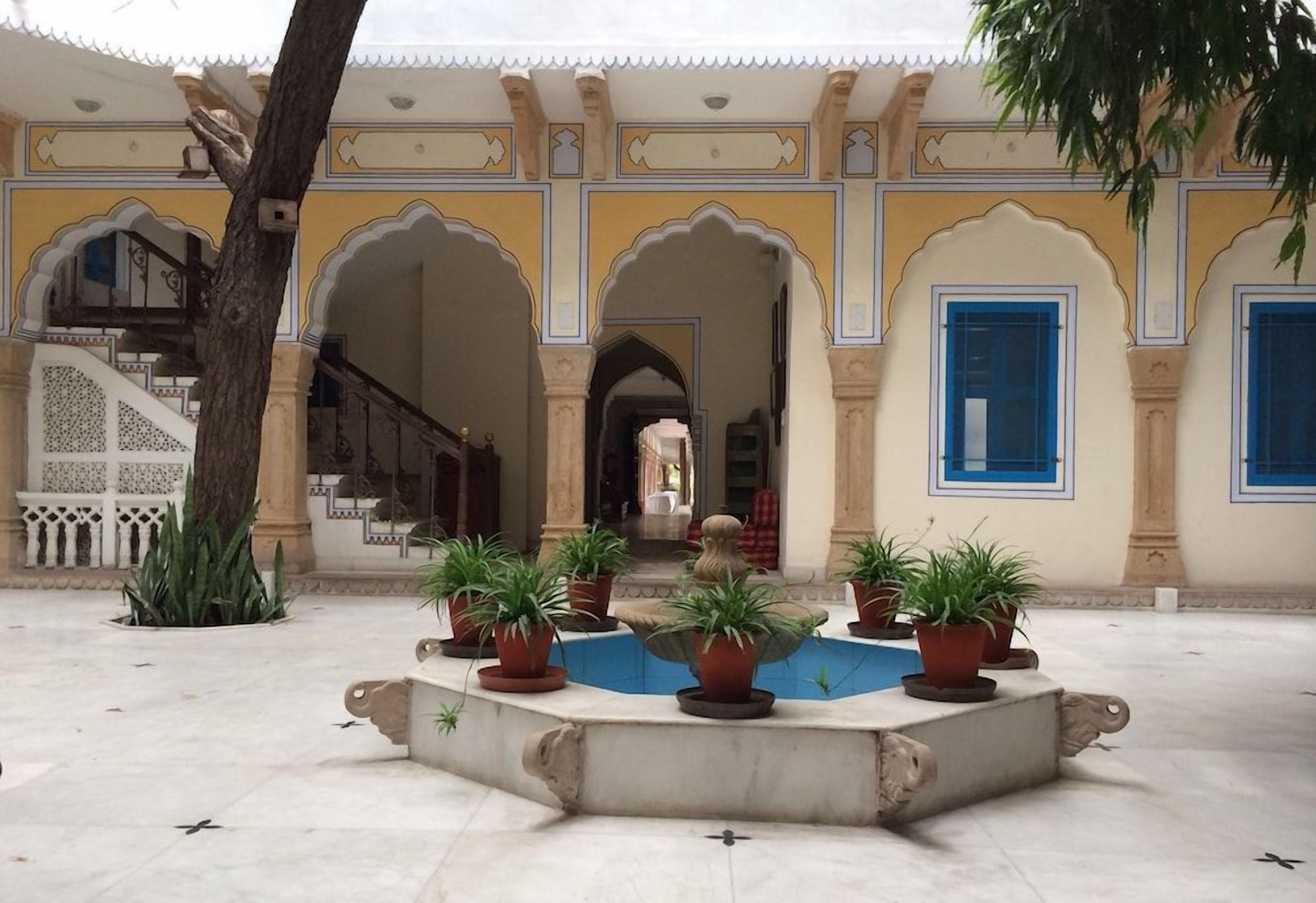 A courtyard with arches, potted plants, and a fountain.