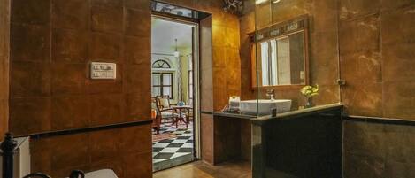A bathroom with a toilet, sink, and mirror. There is a door leading to a dining area.