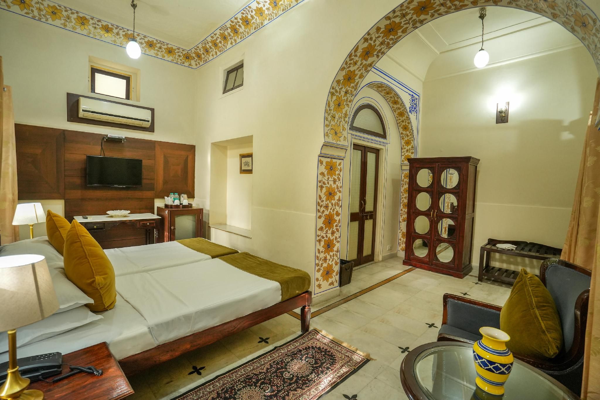 A hotel room with a bed, a television, a desk, a cabinet, and a bathroom.