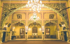 Un interior ornamentado con un gran candelabro, techos abovedados y detalladas decoraciones en las paredes.