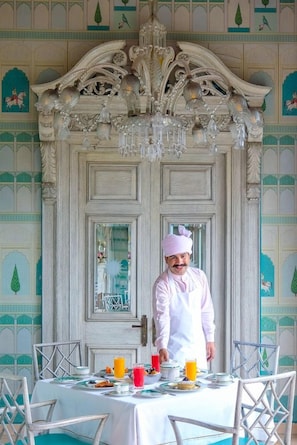 Un coin repas avec une table mise pour le petit-déjeuner, une personne vêtue d’une tenue de chef, et des détails architecturaux raffinés.