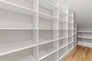 A section of a room with white metal shelving units against a wall, with a wooden floor visible at the bottom.