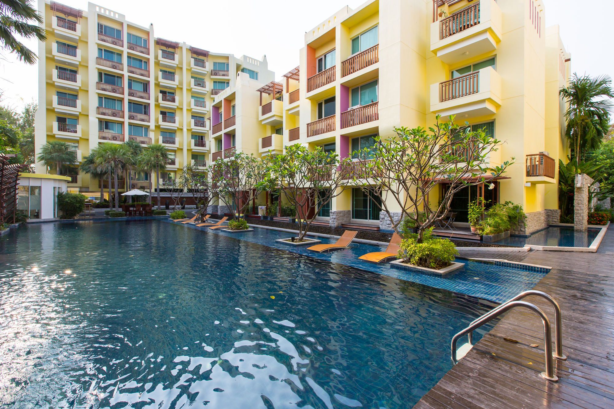 Un hotel con piscina, varios balcones y abundante vegetación.