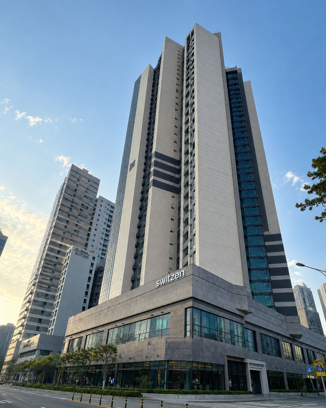A high-rise building with a prominent 'switzerland' sign on the facade, surrounded by other tall buildings.